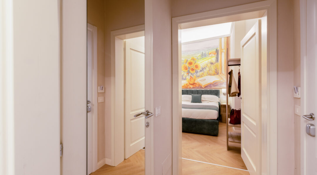Entrance of the family room with corridor and doors leading to two connecting bedrooms, one featuring a sunflower wall painting above the bed.