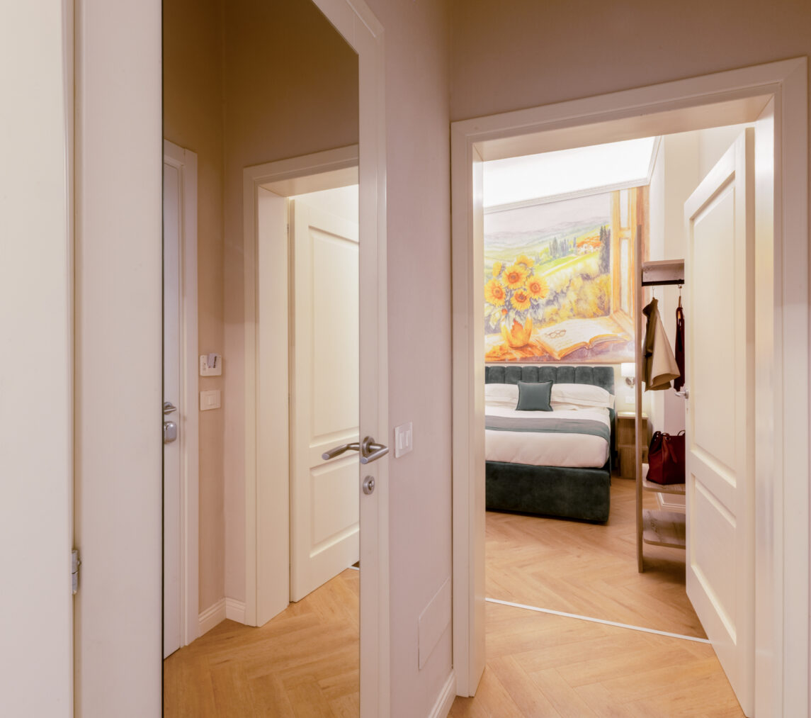 Ingresso della camera familiare con corridoio e porte che conducono alle due stanze comunicanti, una delle quali con dipinto murale di girasoli sopra il letto.
