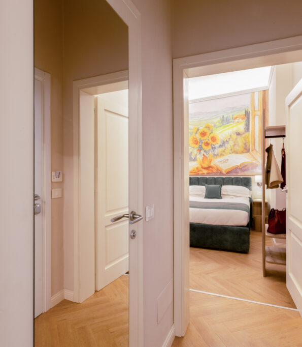 Entrance of the family room with corridor and doors leading to two connecting bedrooms, one featuring a sunflower wall painting above the bed.