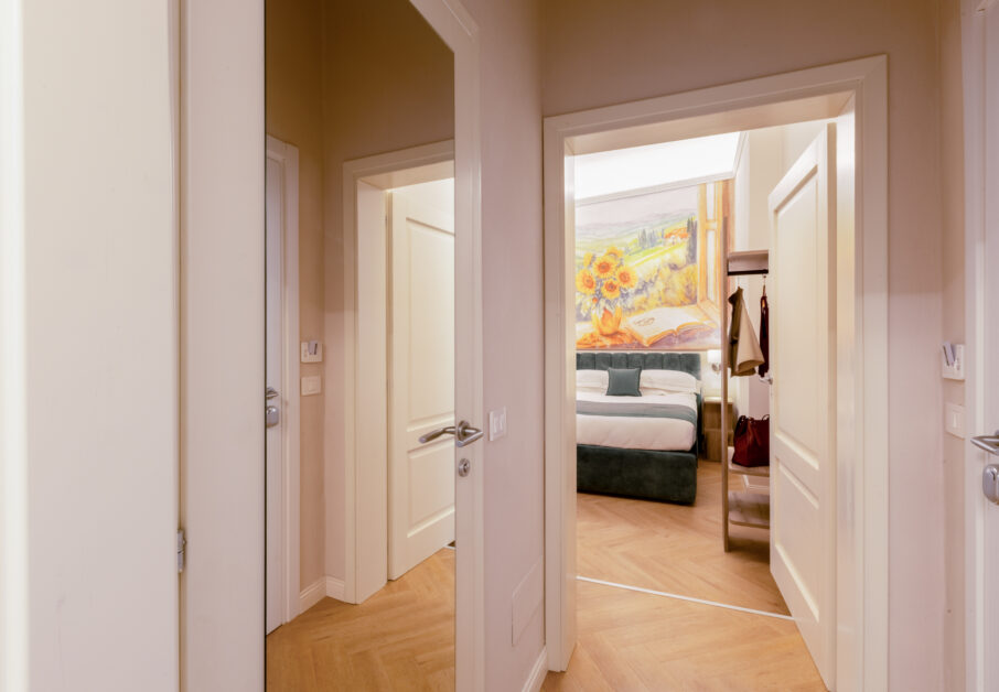 Entrance of the family room with corridor and doors leading to two connecting bedrooms, one featuring a sunflower wall painting above the bed.