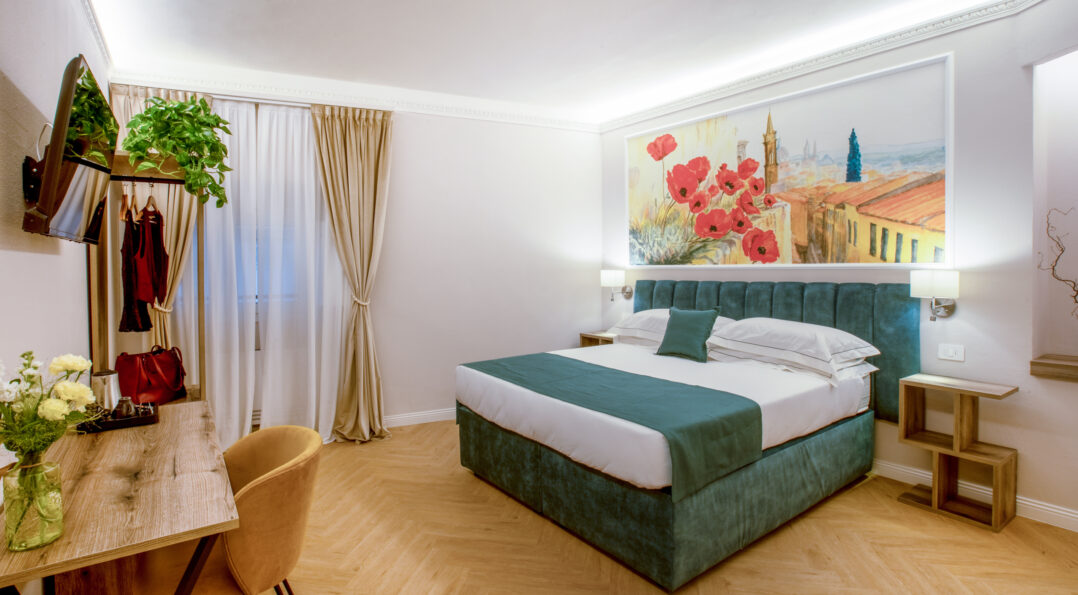 Double room with a green bed, wooden desk, beige curtains, and a large painting with red poppies.