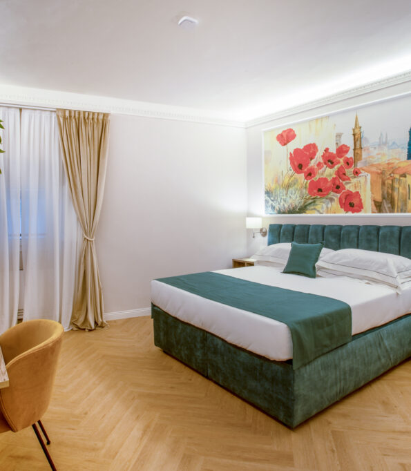 Double room with a green bed, wooden desk, beige curtains, and a large painting with red poppies.