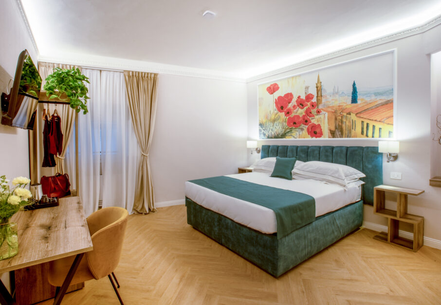 Double room with a green bed, wooden desk, beige curtains, and a large painting with red poppies.