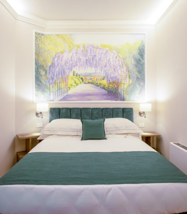 Camera singola con letto matrimoniale alla francese, testata verde e grande affresco sopra il letto raffigurante un tunnel di glicine in fiore.